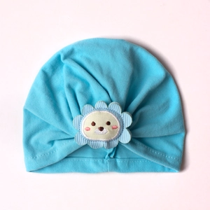 Detail of baby blue pleated turban hat with a cute cartoon lion embroidery patch