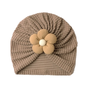 Detailed macro shot of baby turban hat featuring mocha waffle fabric and floral accent