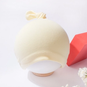 Detail of baby knot hat in pale yellow ribbed cotton on a white model head