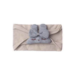 Detailed close-up of soft beige nylon baby headband with a cute grey plush doll decoration