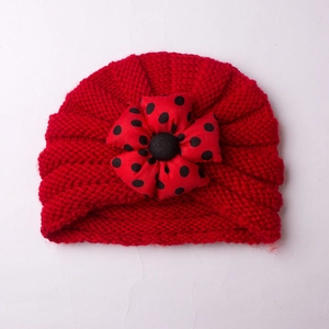 Detailed view of red knitted baby turban featuring a large polka dot fabric flower detail