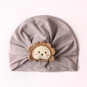 Detail of baby turban hat featuring a cute cartoon lion patch with corduroy ears