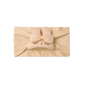 Macro shot of a soft beige nylon infant headband with embroidered eyelash plush bow