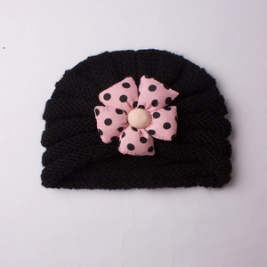 Detail of baby turban hat featuring black knit texture and pink polka dot floral decor