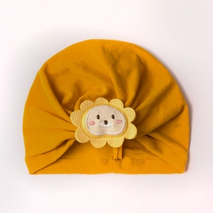 Close-up of baby beanie with soft yellow knit fabric and cute lion patch embroidery