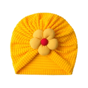 Detail of yellow ribbed baby hat featuring a large 3D floral accent and soft fabric