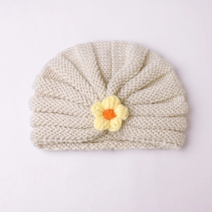 Detailed close-up of cream white ribbed baby turban hat with a yellow knit flower decoration