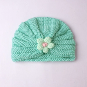Close-up of mint green knitted baby hat with handmade crochet flower detail
