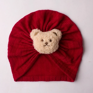 Detailansicht der roten Baby-Strickmütze mit niedlichem Plüschbären-Ornament