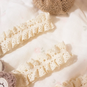Detail of cream lace hairband with intricate crochet patterns and soft ruffled edges