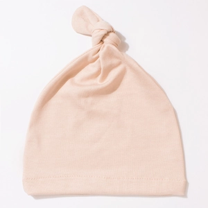Close-up of soft light pink newborn knotted baby hat made from premium knit fabric
