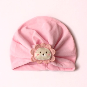 Detail of baby pink turban hat with cute lion embroidery and soft pleated cotton texture