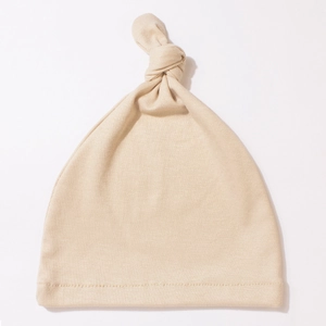 Close-up of soft ribbed texture and durable stitching on a beige baby top knot hat