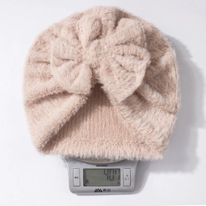 Lightweight 40g plush baby beanie with decorative bow detail on a kitchen scale