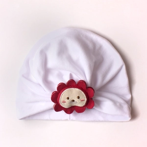 Close-up of white pleated cotton baby turban with red lion sunflower embroidery