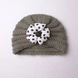 Detail view of baby grey knit turban hat featuring a black and white polka dot fabric flower