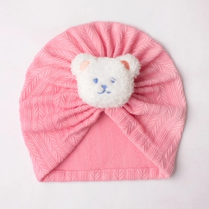 Nahaufnahme der rosa Baby-Turbanmütze mit weißem Plüschbären und strukturierter Zopfstrick-Optik