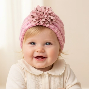 Gros plan d'un bonnet turban tricoté rose pour bébé avec une grande fleur décorative
