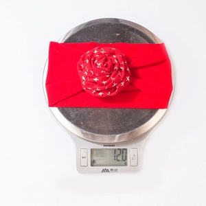 Detail shot of a red floral baby headband weighing 12.0g on a digital scale