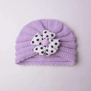 Close-up of lilac baby knit hat with large black and white polka dot flower detail