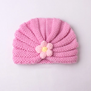 Detail of pink knitted baby turban hat with a cute handmade crochet flower decoration