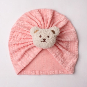Detail der rosa gestrickten Babymütze mit süßem weißen Plüschbären und Zopfstrickmuster
