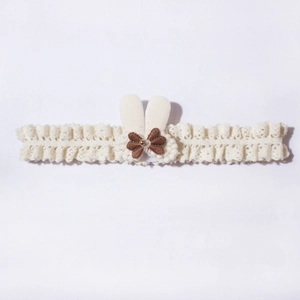 Detail of baby lace headband featuring off-white bunny ears and brown bow with golden bead