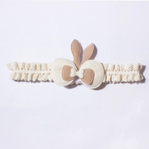 Detail of baby elastic lace headband with cute rabbit ears and bow in beige and brown