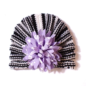 Détail d'un turban rayé pour bébé avec une grande décoration florale violette