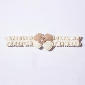 Detailed close-up of cream lace baby headband featuring a soft fabric floral bow