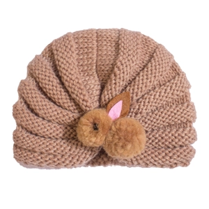 Close-up of brown knitted baby turban hat with 3D plush rabbit ears and soft texture