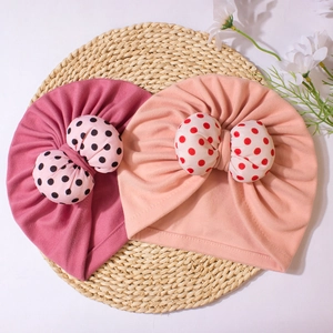 Soft knitted baby turban hats with polka dot bows in pink and beige for newborns