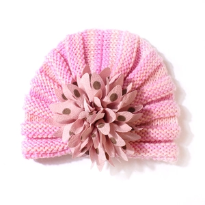 Détail du bonnet en tricot rose rayé pour bébé avec une grande fleur à pois 3D