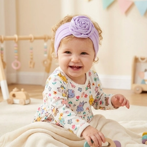 Close-up of a baby in a printed cotton bodysuit and lavender floral elastic headband