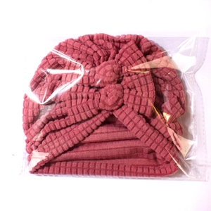 Close-up of pink knitted baby hat with textured fabric and soft double bow detail