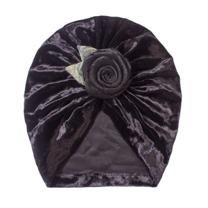 Detailaufnahme des schwarzen Baby-Turbans aus Samt mit Rosenblüte und Metallblättern