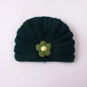 Detailed close-up of dark green knitted baby hat with yellow-centered flower decor