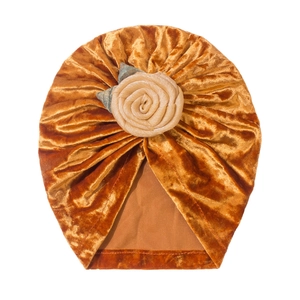 Detail eines Baby-Turbans aus Samt mit bernsteinfarbenen Falten und dekorativer Rose