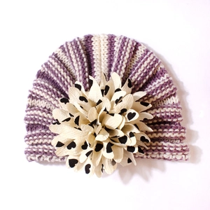 Gros plan du bonnet turban rayé pour bébé avec grande fleur décorative à cœurs
