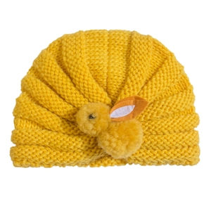 Detail of a bright yellow knitted baby hat with a 3D plush bunny doll decoration