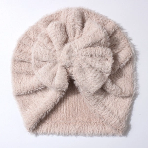 Close-up detail of plush pink baby hat showing soft faux mink texture and bow detail