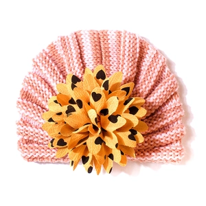 Détail d'un turban pour bébé rayé rose et blanc avec un grand ornement floral jaune