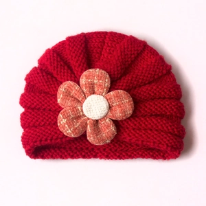 Gemütliche rote Baby-Strickmütze mit einer großen, orangefarbenen Karostoffblume vorne