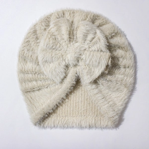 Close-up of cream knit baby turban hat featuring a soft plush texture and large bow detail
