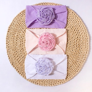 Detailed view of elastic nylon baby headbands with large fabric rose flowers in three colors