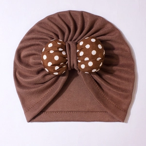 Detailed view of dark brown baby turban hat with a large white polka dot bow