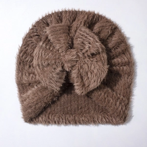 Detail of soft brown plush knit baby hat with a large decorative bow and fuzzy texture