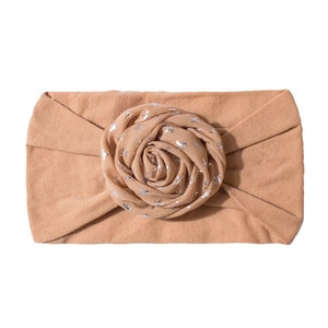 Detailed view of baby flower headband with silver star prints on soft brown elastic fabric