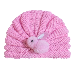 Close-up of pink knitted baby hat featuring a soft plush rabbit and textured weave