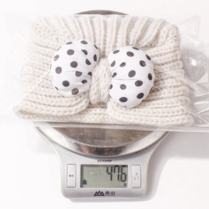Weight measurement of white knitted baby headband with polka dot bow showing 47.6g